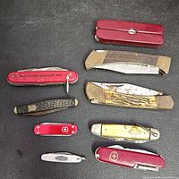 All nine pocket knives laid out on black background
