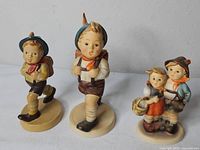 Three Goebel Hummel figurines on white surface