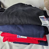 Stack of four folded Jerzees sweatshirts in black, navy and red