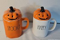 Front view of both mugs showing colors, text, and lids