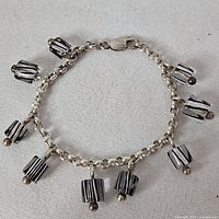 Full view of sterling silver charm bracelet with eight striped cylindrical charms