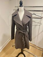 Front view of Tahari wool ruffled trench coat on mannequin showing ruffle detail and belt