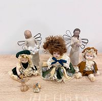 Group shot of all seven items: three dolls, two Willow Tree angels, enamel pin, wire crystal angel