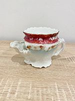 Side view showing handle, spout, floral body and red rim