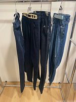 Four pairs of jeans hanging on rack showing overall condition and color range