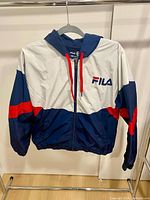 Front of FILA windbreaker on hanger showing color block design and logo