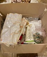 Top view of box showing curtain, angel lantern, glass vase with pebbles, white linens