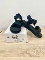 Sandals displayed on top of box showing side profile and logo on box