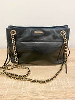 Front view of black leather bag with gold chain strap and exterior pocket