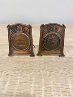 Front view of both bronze-tone plaques showing medallions and crest