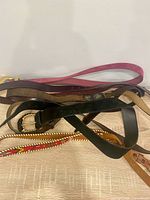 All six belts layered together showing variety of colours and styles