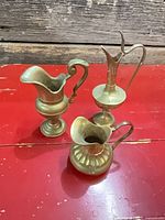 All three brass pitchers grouped on table