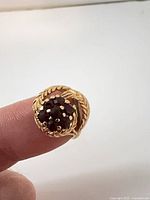 Top view of gold ring showing red stone cluster and braided leaf detail