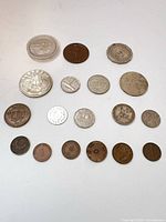 Overview of 18 mixed coins arranged on white surface