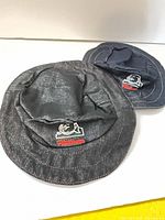 Front view showing both denim bucket hats with logos visible