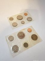 Two sealed Canadian coin sets showing both sides of cellophane packs