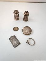 All six silver items grouped: two salt shakers, bar pendant, locket, dime, ring
