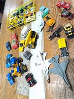 Group shot of assorted vehicles including display rack, Tonka truck, front loader, jets and multiple cars