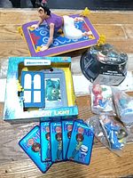 Group shot of all items: Monsters Inc night light, Aladdin on carpet, M&M’s package, Smurf figures bag, Home patches