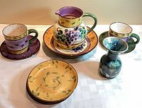 Full set view: pitcher on bowl, two mugs on plates, small vase