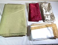 All linens laid out: folded green tablecloth, three napkin sets