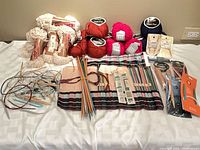Wide view of entire lot: yarn skeins, straight needles, circular needles, needle roll