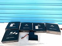 Front view showing five boxed Arc'teryx Voltair batteries and two loose battery packs