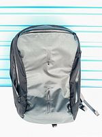 Front view of Arc’teryx Elite 16 backpack showing grey front panel, three vertical zippered pockets, black side panels