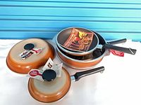 Entire set of three pans stacked with two lids, showing exterior color and handles