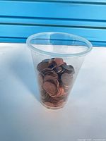 Plastic cup filled with pennies, side view