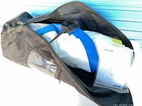 Bag opened showing rolled white and blue inflatable board and manual