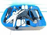 Top view of drone, batteries, propellers, charger, pouch in foam insert