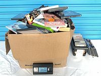 Cardboard box filled with DVDs plus a Titanic VHS tape in front; CDs visible on side