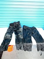 Both pairs of black motorcycle pants laid flat on table