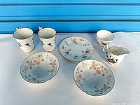 Two tall cups, three bowls, one plate, one creamer laid out