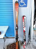 Both pairs of Atomic skis leaning against wall