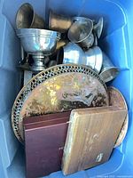 Overview of blue tote containing metal goblets, tray, wood boxes