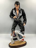 Tall Phoenix Elvis doll standing behind smaller Aloha figurine on base