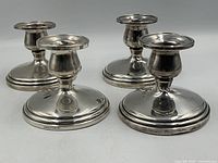 Front view of all four Birks sterling weighted candlestick holders