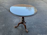 Full view of walnut flip-top table with glass top on asphalt surface