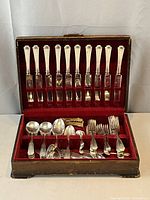 Open wooden flatware chest showing two tiers of Heppelwhite pattern silver-plate flatware