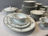 Overview of stacked plates, platters, gravy boat, covered dish
