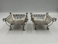 Both sterling silver bonbon dishes, angled front view showing fret-cut pattern and feet