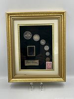 Full view of framed shadow box showing all coins and stamp