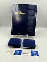 Front view showing program, two closed velvet pin boxes, two ticket stubs