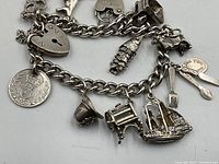 Curb-link sterling bracelet showing heart padlock clasp and multiple charms
