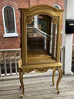 Full view of gilt wood display cabinet on porch