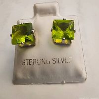 Front view of peridot stud earrings on card stamped 'STERLING SILVER'