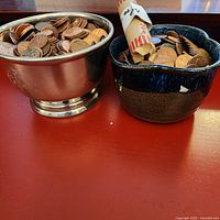 Two bowls of pennies on red surface