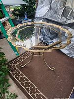 Full view of table showing glass top, brass rim, wrought iron legs